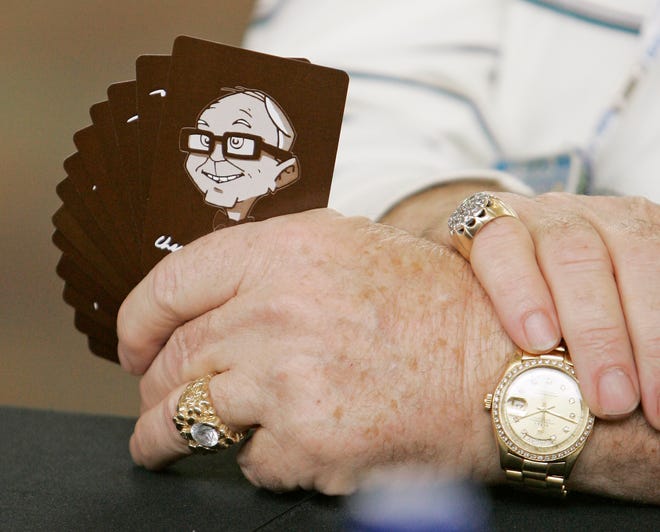 An investor holds cards with a cartoon of Charlie Munger, Vice Chairman of Berkshire Hathaway while playing cards during the annual Berkshire Hathaway shareholders meeting, in Omaha, Neb., Sunday, May 4, 2008.
