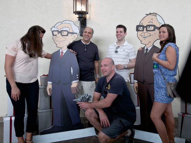 Shareholders pose with cardboard cartoons of Berkshire Hathaway chairman and CEO Warren Buffett, left, and his vice chairman Charlie Munger outside the Berkshire-owned Borsheims jewelry store in Omaha, Neb., Friday, May 4, 2012. Berkshire Hathaway is expected to have 30,000 shareholders come to Omaha for it's annual shareholders meeting this weekend.