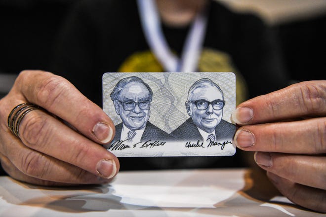 A woman shows a card with photos of Warren Buffett (L) and Charlie Munger during the Shareholder Shopping Day at the Berkshire Hathaway Shareholders Meeting at CHI Health Center in Omaha, Nebraska on April 29, 2022.