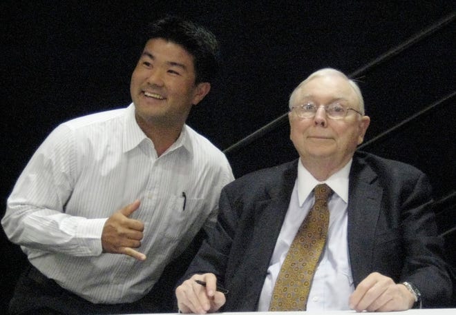 Charlie Munger, right, Vice-Chairman of Berkshire Hathaway, as well as chairman, CEO and president of Wesco, a Berkshire Hathaway subsidiary, get photographed with an unidentified fan, Wednesday, May 7, 2008, in Pasadena, Calif, at the Wesco shareholders meeting. Munger said Wednesday investors should lower their expectations because the economic conditions many people used to build wealth over the past three decades aren't likely to be repeated.